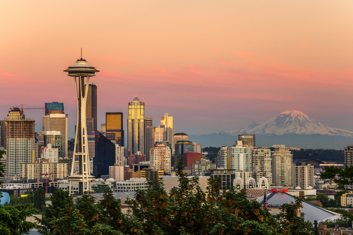 Seattle skyline at sunset showing the Space Needle in the foreground and Mount Rainier in the background
