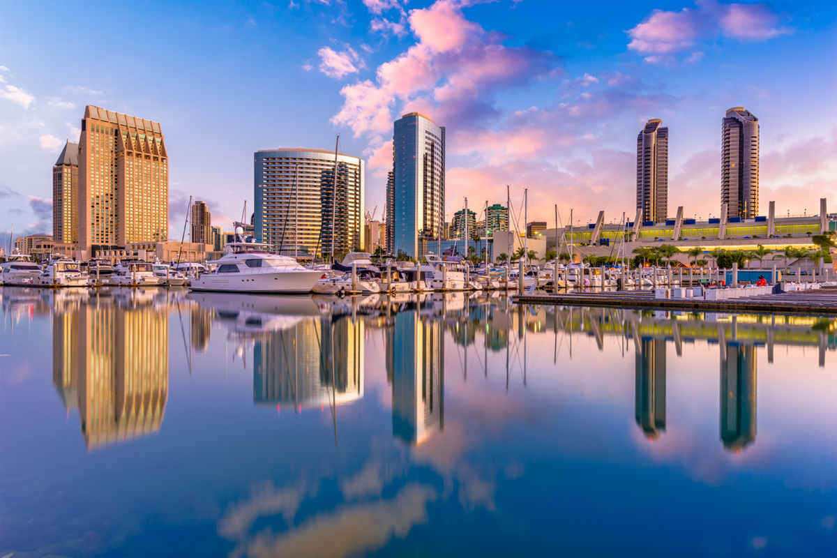 San Diego harbor skyline at sunrise with boats docked and buildings reflected in calm water