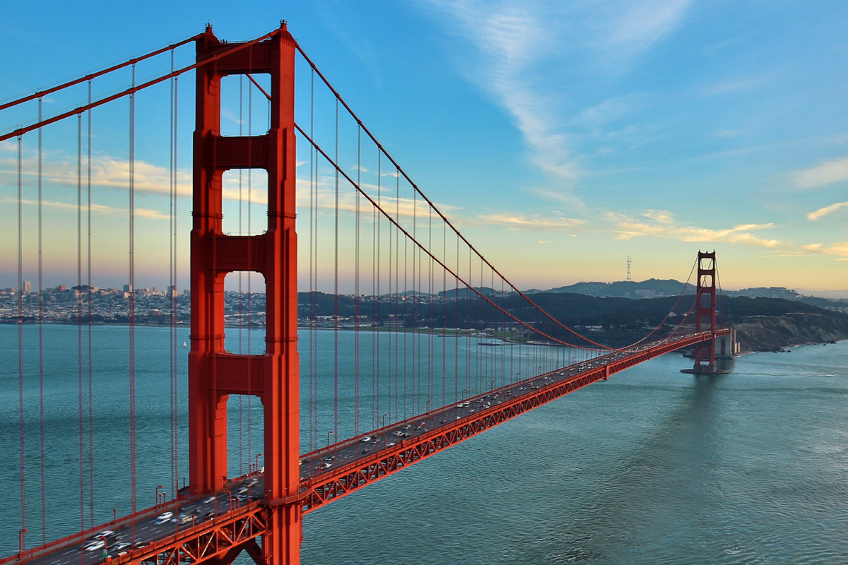 Golden Gate Bridge spanning San Francisco Bay at sunset with city skyline and hills in the distance