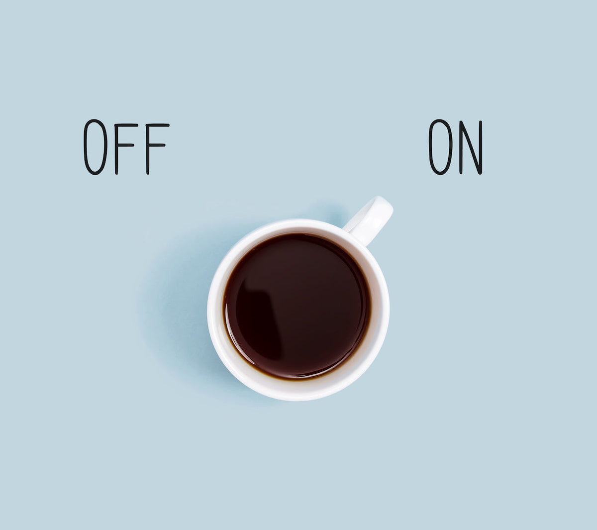 Top-down white cup of black coffee between the words OFF (left) and ON (right) on a pale blue background