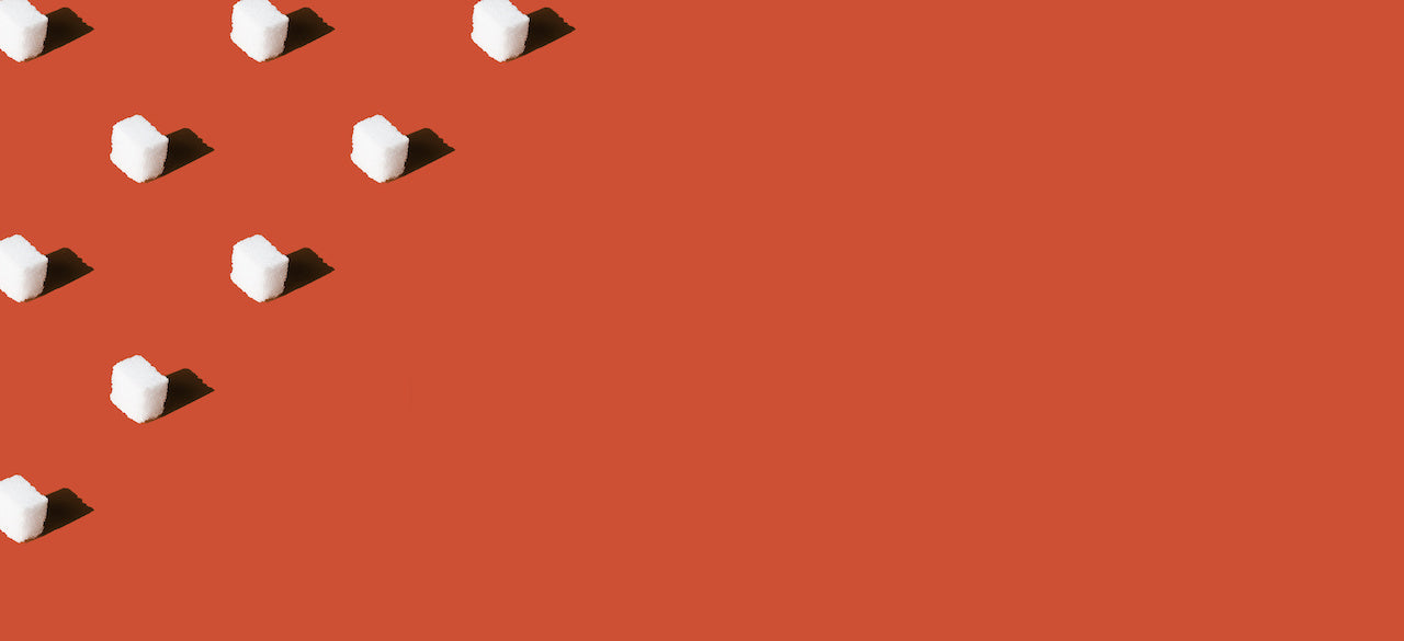 Diagonal row of white sugar cubes casting shadows on a flat terracotta background, minimalist composition with empty space